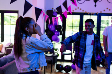 Friends celebrating at home, dancing and enjoying festive decorations and balloons