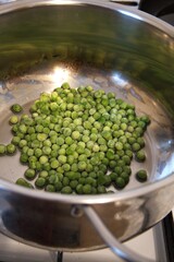 Close-up view of frozen green peas in a cooking pot. Healthy vegetable concept.