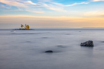 A stunning sunset over a serene beach in Tiny, Ontario, capturing the tranquil beauty and vibrant colors of the evening sky reflecting on the calm waters.