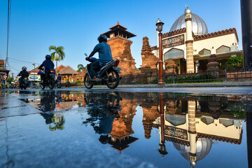 Historic Menara Kudus Mosque with Clear Blue Sky Background and water reflection in Central Java