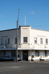 Cream-colored brick building with a flat roof. The building has a vintage feel, with multiple white-framed windows and a small awning above the ground-floor windows. 