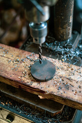 Drilling machine view up to bottom at an angle. The drill chuck and the drilling blank on the machine lie in the middle of the chips. High quality photo