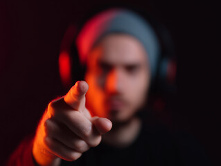 Man with headset pointing finger forward, intense expression, blurred background, red lighting, esports competitor, focused, gaming mood