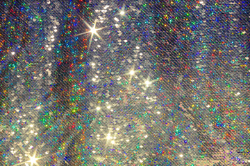 Festive sparkling background with silver sequins reflecting multicolored light.