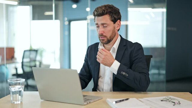 Professional businessman in a dark suit works on laptop in a modern office. Experiencing allergy symptoms, businessman applies nasal spray, feeling instant relief and happiness.