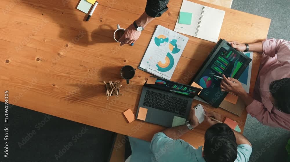 Aufkleber Smart project manager calling phone while diverse team brainstorm idea and looking at financial statistic at tablet at meeting table. Diverse business people planning marketing strategy. Convocation.