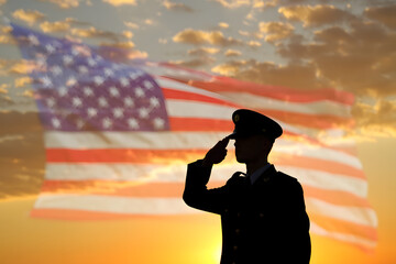 Silhouette of a young couple on the beach holding USA flags at sunset
