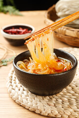 Hot Spicy Noodles in Bowl with Chopsticks - Asian Sour Soup with Chili Sauce on Wooden Table