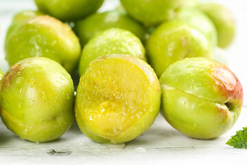 Fresh Green Plums with Water Droplets on White Wood Background