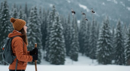 Young woman enjoying a winter hike in a snowy mountain forest. Outdoor adventure and nature travel concept.