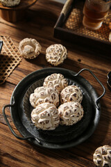 Dried Shiitake Mushrooms with Carved Flower Patterns in Cast Iron Pan on Wooden Table
