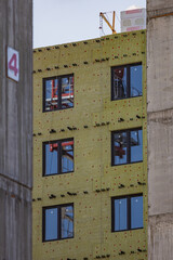 The blue sky is reflected in the windows of a multi-storey building under construction.