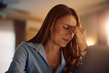 Exhausted woman having headache while working on computer at home.
