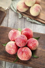 Fresh Chinese Peaches from Guangshui Hubei Province on Rustic Wooden Board with Traditional Chopsticks