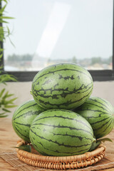 Fresh Whole Watermelons in Wicker Basket on Wooden Table with Tropical Background