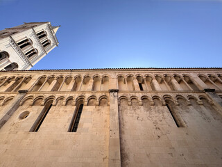 Fototapeta premium detail of the facade of the Cathedral of St. Anastasia with bell tower against clear blue sky in Zadar, Croatia