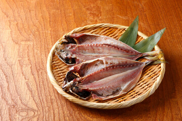 ザルに盛った2枚の鯵の開き　木目背景