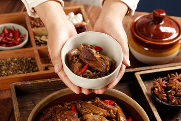 Traditional Chinese Braised Goose Stew in Hands with Spices and Clay Pot Cooking Setup