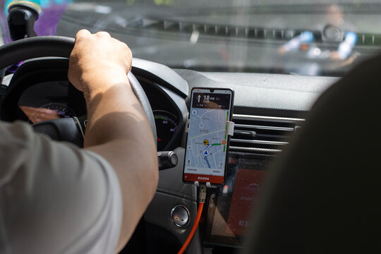 Shanghai, China - July 4, 2023: A Chinese rideshare driver uses the Dida Taxi app from his phone to provide transportation services in Shanghai, China. Dida Chuxing is a Chinese ridesharing platform.