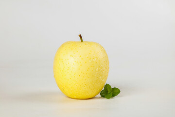 Fresh Yellow Apple with Mint Leaves and Water Droplets on White Background