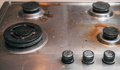 Dirty stove with food leftovers. Unclean gas kitchen cooktop with greasy spots, old fat stains, fry spots and oil splatters.
