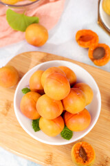 Fresh Xinjiang Apricots in White Bowl with Mint Leaves on Wooden Board - Healthy Organic Stone Fruit