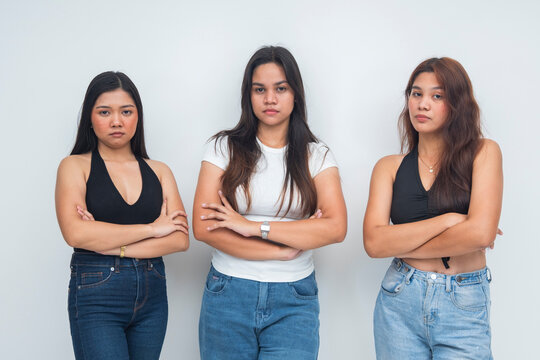 A group of young Asian women with folded arms and judgmental expressions, giving a snubby, mean girl vibe, half body shot. Isolated on a white background.