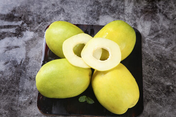 Fresh Yunnan Papaya Fruit Display with Cut Halves Showing White Pulp and Seeds on Dark Plate