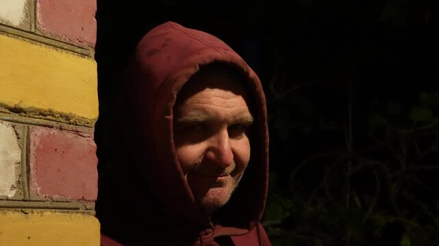 4K video of a strange man in hoodie standing near a wall at night. Dark cinematic scene symbolizing danger, crime and suspicious behavior