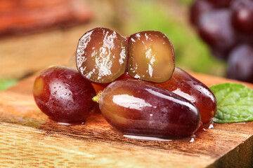 Fresh Red Grapes Cut in Half Showing Sweet Juicy Flesh on Wooden Board