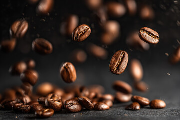 Fototapeta premium Coffee beans falling in mid-air against a dark background