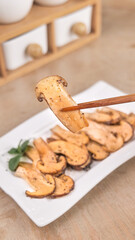 Fresh Cooked Agaricus Mushrooms with Chopsticks - Yunnan Cuisine Style Golden Wild Mushroom Slices on White Plate
