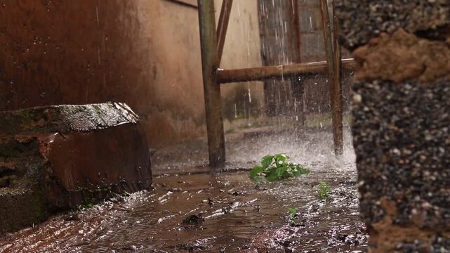 Water flowing from a water tower falling on the streets of an alley in a rural Nigerian village