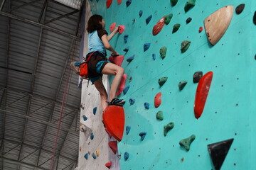 Senior Asian woman exercising and practicing rock climbing in gym. Extreme sports and health...