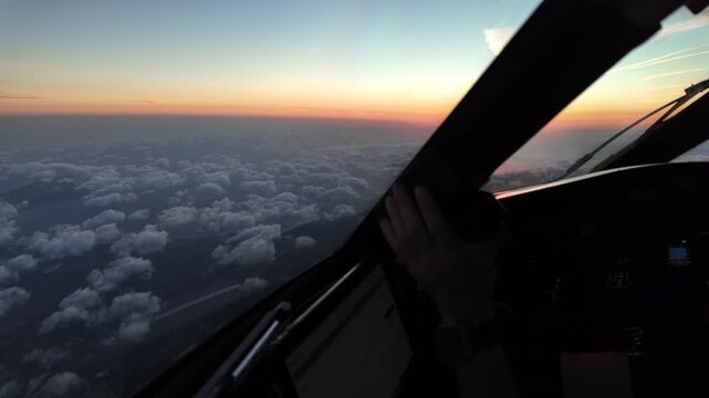 An immersive pilot&rsquo;s eye view taken from inside a jet cockpit while flying at sunrise over the Mediterranean Sea, with a radiant rising sun in the horizon, and few clouds in the horizon.