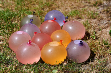 Water balloons on a grassy patch, prepared for an outdoor activity. The colorful balloons add a playful atmosphere to the scene, waiting for action.