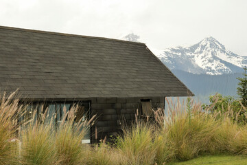 Obraz premium Cabin among tall grass and mountains in beautiful day