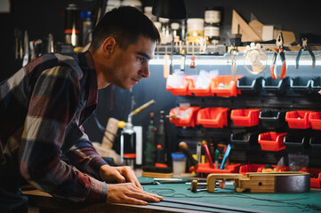 Working process of the leather belt in the leather workshop. Man holding crafting tool and working