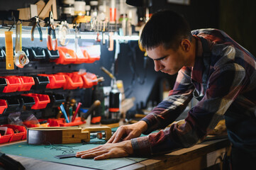 Working process of the leather belt in the leather workshop. Man holding crafting tool and working