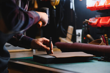 Man working with leather. Professional makes a wallet.