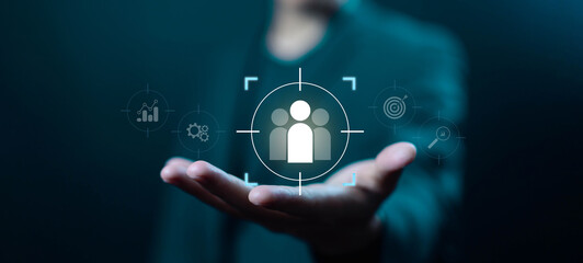 Businessman hand holding digital target audience icon, symbolizing customer focus, market analysis, audience segmentation, business strategy, and data-driven decision-making in corporate marketing.