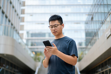 Fototapeta premium man in a blue T-shirt holds a phone in an urban area