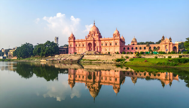 Magnificent pink palace with domes reflected in a calm lake under a blue sky, Ahsan Manzil