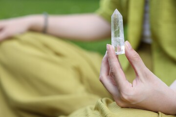 Woman meditating with crystal to heal or restore her aura outdoors, closeup