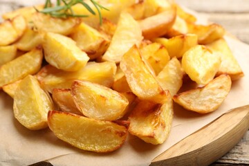 Tasty baked potatoes with rosemary on wooden table, closeup