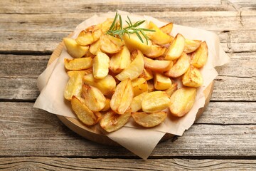 Tasty baked potatoes with rosemary on wooden table, closeup