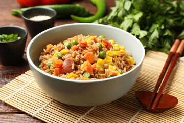 Tasty fried rice in bowl on wooden table, closeup