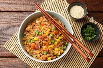 Tasty fried rice in bowl on wooden table, flat lay