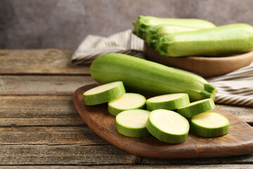 Fresh ripe zucchinis on wooden table, closeup. Whole and cut