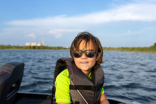 Smiling boy in sunglasses on a boat ride across the lake